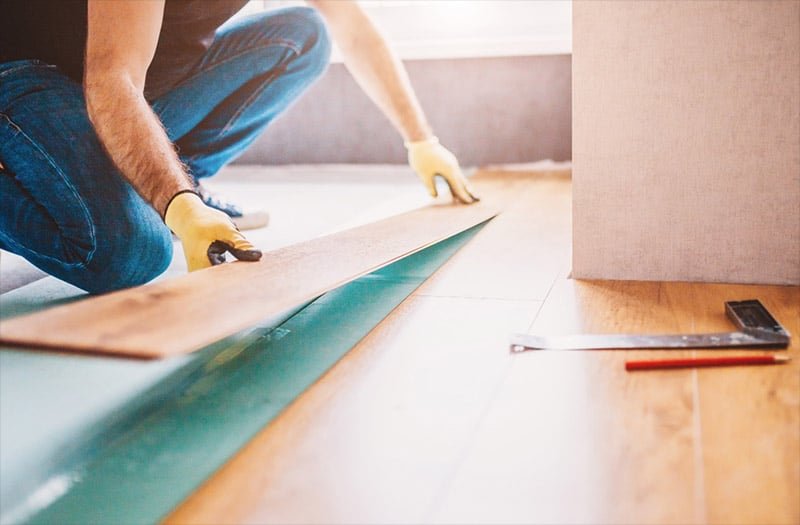 Installer positioning a wood-look flooring plank