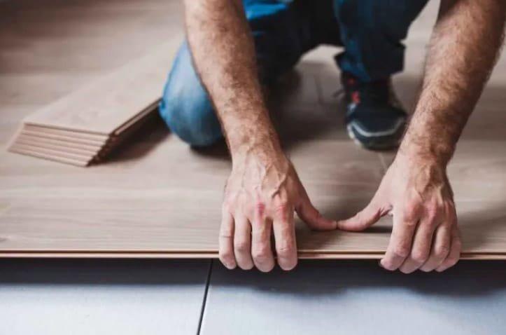 Installer pressing a plank into place in a floating floor